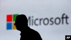 FILE - A man is silhouetted as he walks in front of a Microsoft logo at an event in New Delhi, India, Nov. 7, 2017. Microsoft says it’s uncovered new Russian hacking attempts targeting U.S. political groups ahead of midterm elections in November.