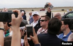 El presidente de EE.UU. Donald Trump levanta una gorra de camuflaje al llegar al aeropuerto internacional McAllen, en McAllen, Texas, en la frontera con México, el jueves 10 de enero de 2019.