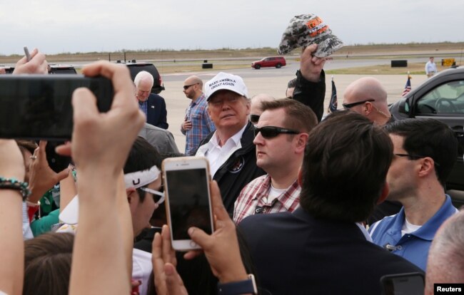 El presidente de EE.UU. Donald Trump levanta una gorra de camuflaje al llegar al aeropuerto internacional McAllen, en McAllen, Texas, en la frontera con México, el jueves 10 de enero de 2019.