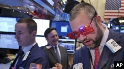 A trader wears glasses in the shape of 2015 while working on the floor at the New York Stock Exchange in New York, Dec. 31, 2014.