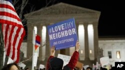 A protester carries a sign in front of the Supreme Court during a protest about President Donald Trump's recent executive orders, in Washington, D.C., Jan. 30, 2017.