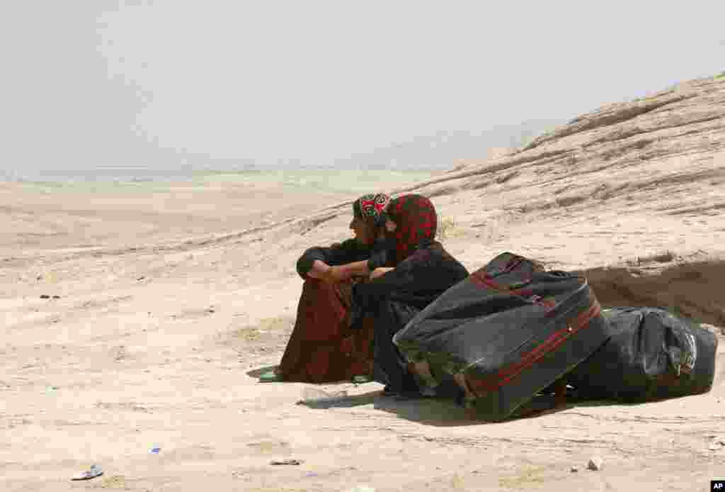 Syrian refugees take a rest as they cross into Iraq at the Peshkhabour border point in Dahuk, August 20, 2013.
