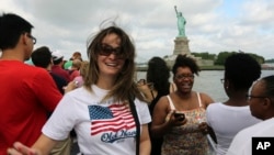 FILE - Visitors to the Statue of Liberty take photos as they arrive on the first tourist ferry to leave Manhattan, July 4, 2013 in New York.