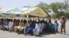 FILE - In this Feb. 12, 2016, file photo, men who were detained by Nigeria army who have no links to Boko Haram sit under a canopy before their release at the Giwa military barracks in Maiduguri, Nigeria. Babies and children are among scores of people dying in military detention at the notorious Nigerian Giwa military barracks where soldiers illegally hold suspected Islamic extremists, Amnesty International charged Wednesday, May 11, 2016.