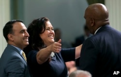 Assemblywoman Lorena Gonzalez Fletcher, D-San Diego, flanked by Assemblyman Ash Kalra, D-San Jose, left, goes to hug Assemblyman Jim Cooper, D-Elk Grove, for his vote for the "sanctuary state" bill she carried in the Assembly, Sept. 15, 2017, in Sacramento, Calif. The Assembly approved the bill, SB54, by Senate President Pro Tem Kevin de Leon, D-Los Angeles, and Gov. Jerry Brown signed it into law Oct. 5, 2017.