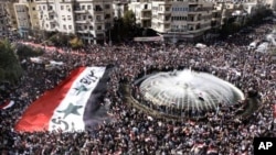 Pro-Syrian regime protesters, carry a giant Syrian flag during a demonstration against the Arab League decision to suspend Syria, in Damascus, Syria, November 13, 2011.