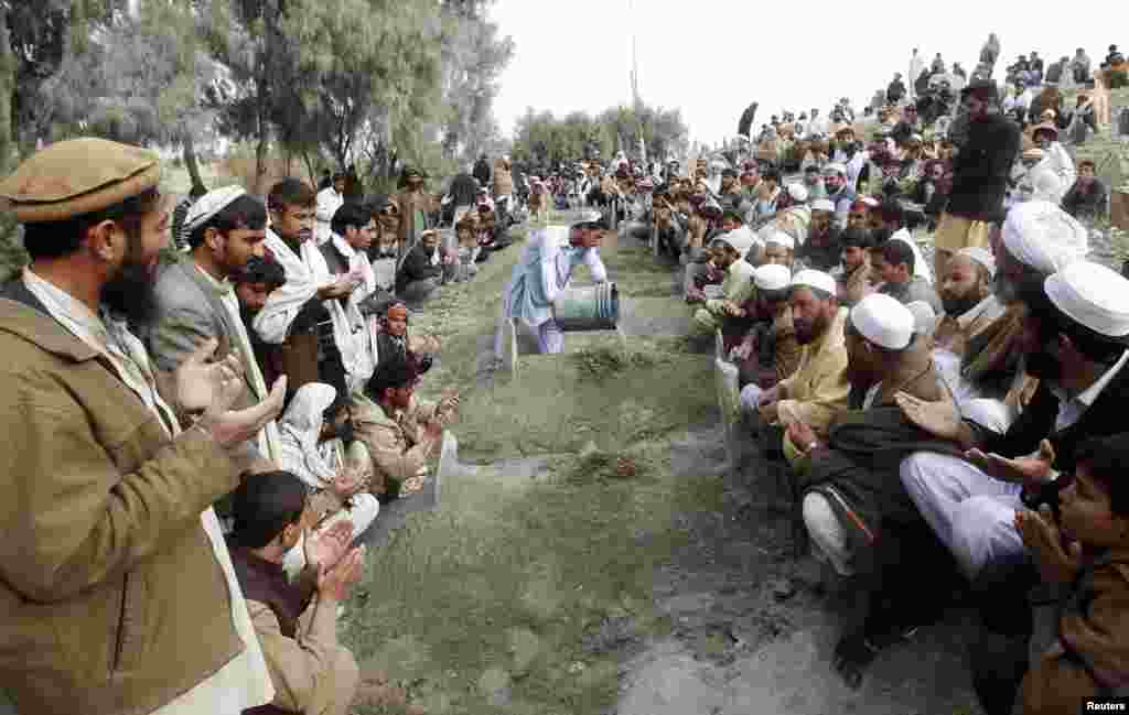 Villagers pray over the graves of girls who were killed by an explosion in Jalalabad, Afghanistan, December 17, 2012.