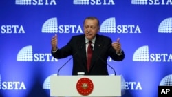 Turkey's President Recep Tayyip Erdogan gestures as he delivers a speech in Ankara, Turkey, Tuesday, Aug. 14, 2018. Erdogan said his country will boycott U.S.-made electronic goods amid a diplomatic spat that has helped trigger a Turkish currency crisis.The Turkish lira has nosedived in value in the past week over concerns about Erdogan's economic policies and after the United States slapped sanctions on Turkey angered by the continued detention of an American pastor. (Pool Photo via AP)