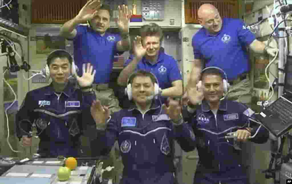 In this NASA image, astronauts (front row from left) Kimiya Yui, of Japan, Oleg Kononenko, of Russia, and Kjell Lindgren, of the United States, wave after boarding the International Space Station, July 23, 2015.