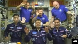 FILE - In this image taken from video from NASA, astronauts, front row from left, Kimiya Yui, of Japan, Oleg Kononenko, of Russia, and Kjell Lindgren, of the United States, wave after they boarded the International Space Station, July 23, 2015. 