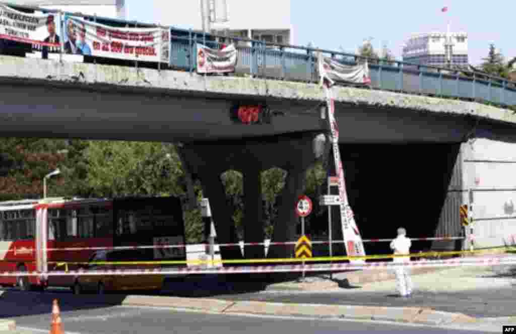 Election campaign banners fly from a overhead bridge as a police forensic officer inspects a blast scene in Istanbul May 26, 2011. A bicycle bomb wounded seven people including a police officer in Istanbul on Thursday, Istanbul's police chief Huseyin Capk