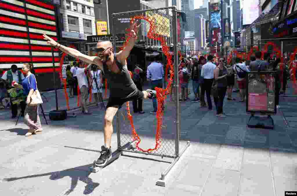 A man leaps through one of a series of 17 sculptures made of copper and steel panels cut out with various sizes of human silhouettes by Cuban-born artist Arles del Rio in New York&#39;s Times Square, New York.