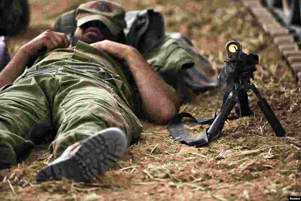 An Israeli soldier sleeps on the ground next to his weapon, near the Gaza Strip, July 15, 2014.