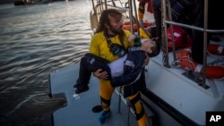 A volunteer carries a young boy after a boat with refugees and migrants sank while crossing the Aegean Sea from Turkey to the Greek island of Lesbos, Oct. 28, 2015. 