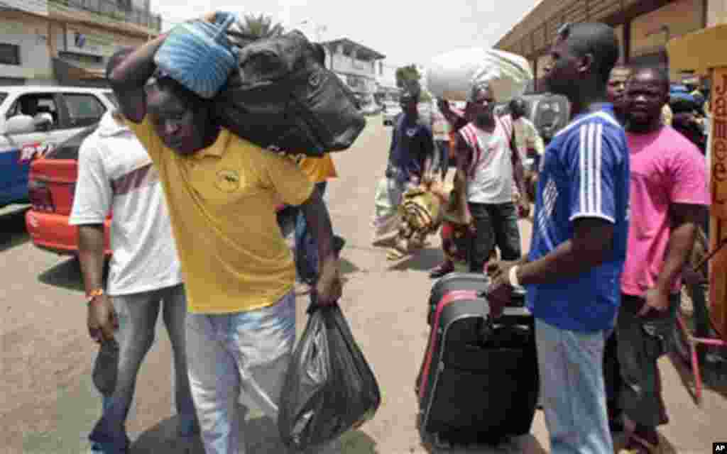 People walk with their belongings towards a railway station as they leave Abidjan, Ivory Coast. Rebel forces backing Ivory Coast's internationally recognized president were advancing toward the capital Wednesday, March 29, 2010