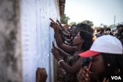 Youth check lists of names to see if they were selected as poll workers for the upcoming general elections in Port Loko, Sierra Leone, March 3, 2018. Youth unemployment is a chronic challenge in the West African nation. (J. Patinkin/VOA)