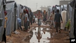 Syrian Kurdish refugees who fled Kobani, go about at a refugee camp in Suruc, on the Turkey-Syria border, Oct. 11, 2014.