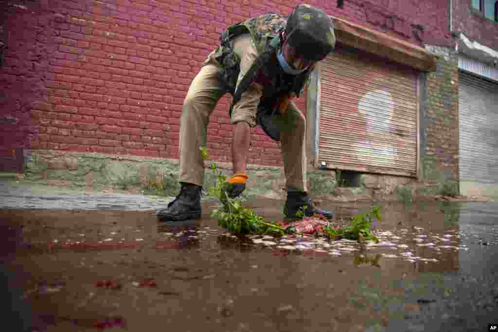An Indian policeman cleans blood on a street with a stick after suspected rebels attacked policemen on the outskirts of Srinagar, Indian-controlled Kashmir.