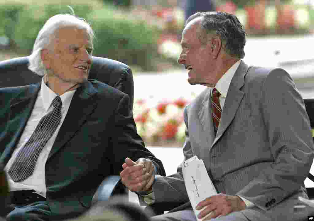 Former President George H.W. Bush, right, takes Billy Graham's hand during a ceremony for the Billy Graham Library in Charlotte, N.C., May 31, 2007. 