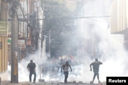 Demonstrators are pictured amid tear gas during a protest as Honduran President Juan Orlando Hernandez is sworn in for a new term in Tegucigalpa, Honduras, Jan. 27, 2018.