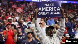 Yon elektè nwa-ameriken ki apiye kandida Donald Trump, pote yon pannkat ki reprann slogan prezidan an: "Ann rebay Lezetazii grandè li ankò." (Foto: Rojters/Leah Millis).