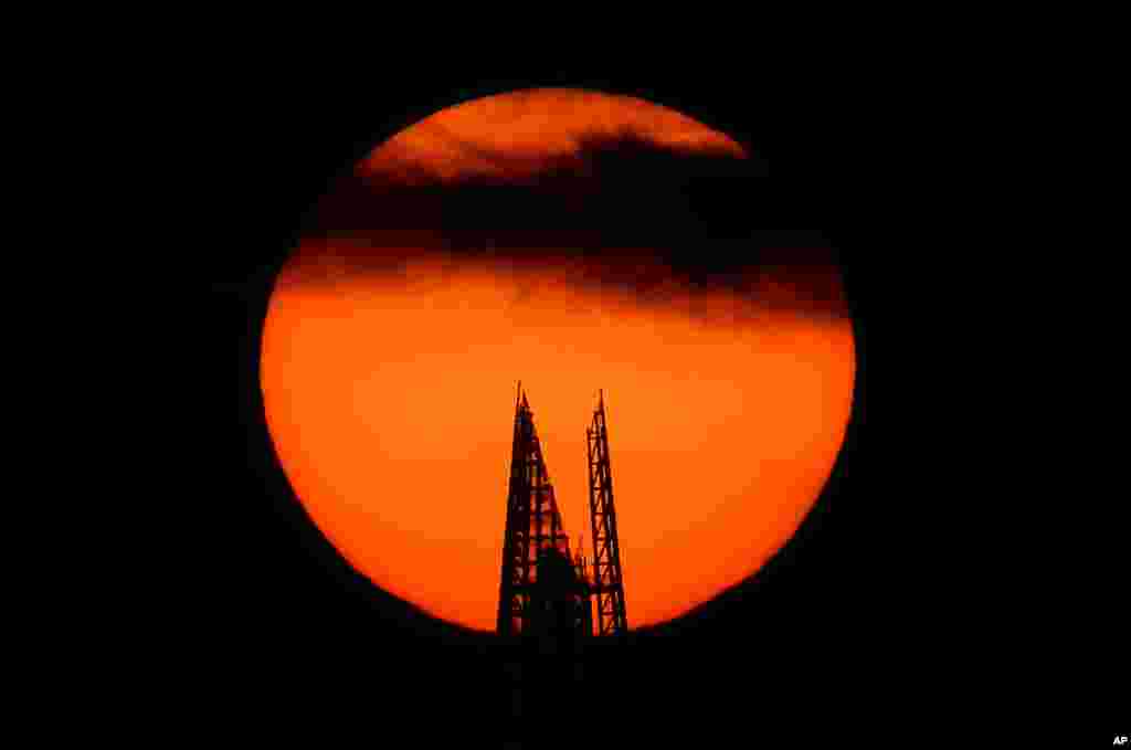 The sun is seen rising behind the top of the Shard skyscraper in London.