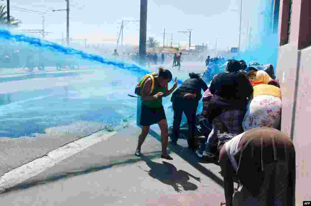 People taking part in a protest against poor sanitation run away from a water cannon and stun grenades fired by members of the South African Police Services in Cape Town.