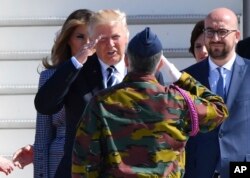 US President Donald Trump, second left, salutes a Belgian soldier as he arrives at Melsbroek Military Airport in Belgium, May 24, 2017. At right is Belgian Prime Minister Charles Michel.