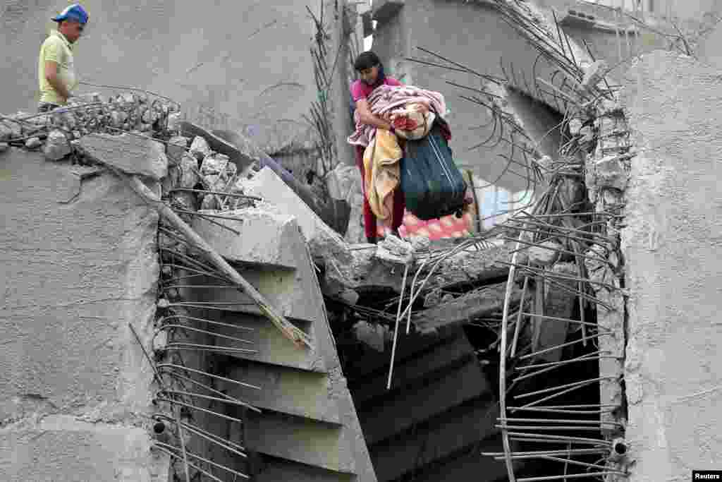 A Palestinian holds his belongings in his house that was destroyed by an Israeli air strike on Gaza City.