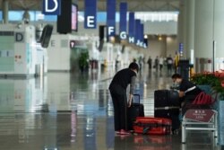 Seorang perempuan mengenakan masker di tengah pandemi COVID-19, memilah barang bawaan di Bandara Internasional Hong Kong di Hong Kong, 20 Oktober 2020. (REUTERS/Lam Yik)