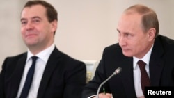 Russian President Vladimir Putin (R) and Prime Minister Dmitry Medvedev take part in a meeting on social and economic development in Moscow's Kremlin, Dec. 23, 2013.