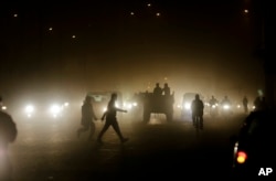 Pedestrians walk through a busy road in New Delhi, India, Dec. 10, 2015.