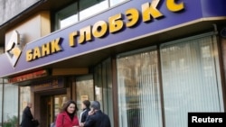 FILE - People walk past a Globex bank office in Moscow, Oct. 16, 2008.