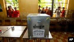 FILE - Young men are seen taking photos of a ballot box at a polling station in Phnom Penh, Cambodia, July 28, 2013.