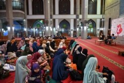 Perempuan (di latar depan) dan laki-laki (di latar belakang) saat menghadiri ceramah agama tentang pernikahan tanpa pacaran di sebuah masjid di Bekasi, di perbatasan timur Ibu Kota Jakarta. (Foto: AFP/Adek Berry)