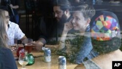 Diana Downard, 26, a Bernie Sanders supporter who now says she will vote for Hillary Clinton, has drinks with friends at a pub in Denver, July 6, 2016. 