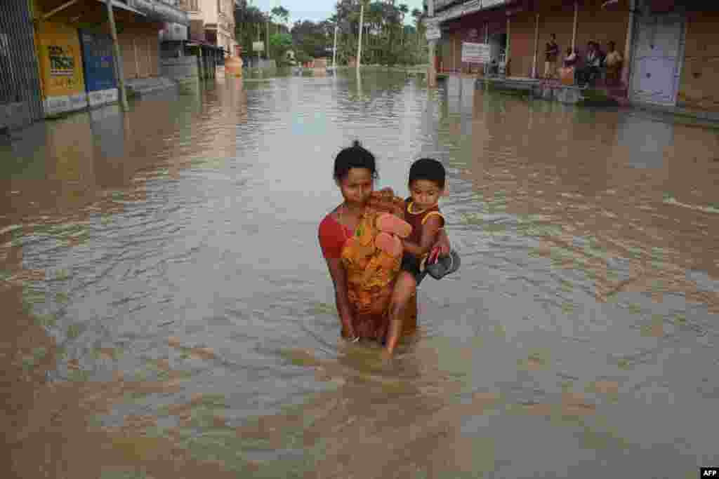 An Indian villager carrying a child wades along a flooded street after heavy downpour in Baldakhal village, on the outskirts of Agartala, the capital of northeastern state of Tripura.