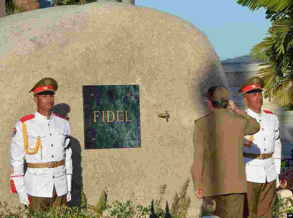 Cuba&#39;s President Raul Castro salutes at the tomb of his older brother Fidel Castro, a simple, grey, round stone about 15 feet high, at the Santa Ifigenia cemetery in Santiago.&nbsp;Raul Castro placed the ashes in a niche in the tomb that was then covered by a plaque bearing the single name,&quot;Fidel.&quot;