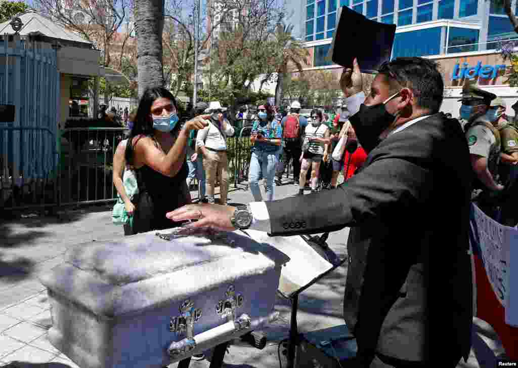 A preacher holds a bible next to an empty child's coffin as a pro-choice activist reacts, outside Congress, where lawmakers will begin to discuss a bill that decriminalizes abortion until the 14th week of pregnancy, in Valparaiso, Chile, Jan. 13, 2021.