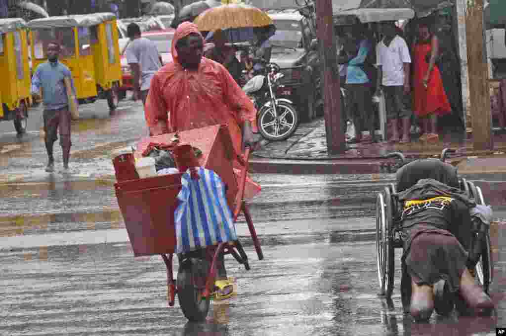 A vendor selling grilled meat, left, walks past an amputee, right, who is suspected of dying from the Ebola virus in Monrovia, Liberia, Sept. 2, 2014.