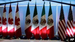 FILE - National flags representing Canada, Mexico, and the U.S. are lit by stage lights at the North American Free Trade Agreement, NAFTA, renegotiations, in Mexico City, Sept. 5, 2017. 