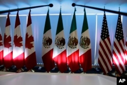 National flags representing Canada, Mexico, and the U.S. are lit by stage lights at the North American Free Trade Agreement, NAFTA, renegotiations, in Mexico City, Sept. 5, 2017.
