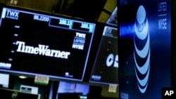 FILE - The logos for Time Warner and AT&T appear above alternate trading posts on the floor of the New York Stock Exchange.