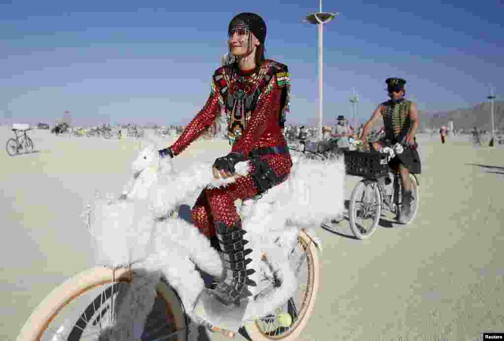 Bibi rides her bike on the Playa during the Burning Man 2015 &quot;Carnival of Mirrors&quot; arts and music festival in the Black Rock Desert of Nevada, USA, Aug. 31, 2015. Approximately 70,000 people from all over the world are gathering at the sold-out festival to spend a week in the remote desert to experience art, music and the unique community that develops.