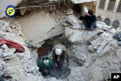 FILE - This photo shows Syrian Civil Defense White Helmets digging in the rubble to remove bodies and look for survivors, after airstrikes hit the Bustan al-Basha neighborhood in Aleppo.