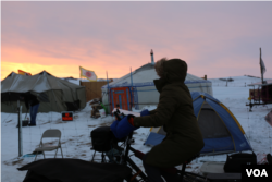 A volunteer pedals a stationary bike set up to power a strip of phone chargers in the media tent of the Standing Rock camp in North Dakota. (E. Sarai/VOA news)