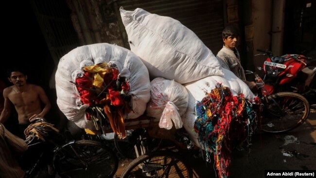 A man is transporting unused leftover fabric from factories at a market in New Delhi, India, November 4, 2021. The fabric will be repurposed to create high-end sustainable clothes. (REUTERS/Adnan Abidi)