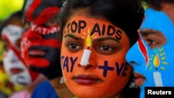 FILE - Students with their faces painted with messages pose during an HIV/AIDS awareness campaign to mark the International AIDS Candlelight Memorial, in Chandigarh, India, May 20, 2018. 