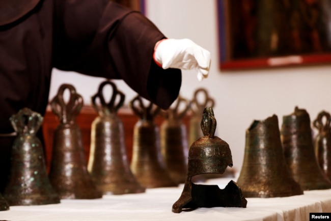 Father Stephane, Franciscan Friar and Liturgist of the Custody of the Holy Land reaches for the remains of a bell, part of a collection from the 12th century. (Reuters)