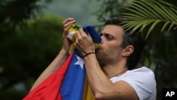 El líder opositor venezolano Leopoldo López besa una bandera venezolana mientras saluda a simpatizantes reunidos frente a su casa en Caracas el sábado, 8 de julio de 2017.